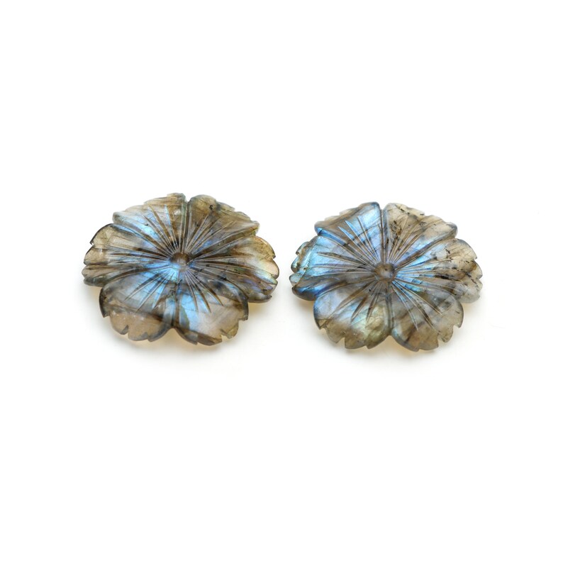 May include: Two iridescent blue and gray labradorite gemstone flower carvings. The flowers have a starburst pattern and are carved in a flat, circular shape.