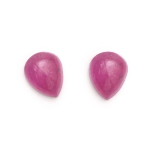 Puede incluir: Dos piedras preciosas de forma de pera rosa, cada una con una superficie lisa y pulida.