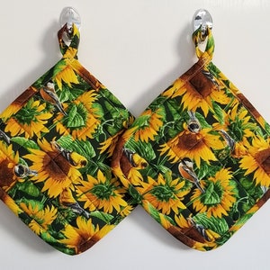 May include: Two quilted pot holders with a sunflower and bird design. The pot holders are green, yellow, and brown with a quilted pattern.