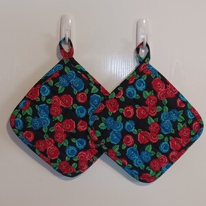 May include: Two black pot holders with a floral pattern of red and blue roses on a black background.