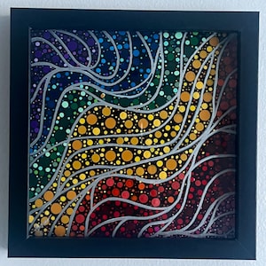 May include: A framed abstract painting with a rainbow color scheme. The painting features a series of white lines that create a wave-like pattern. The background is filled with small, colorful dots.