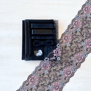 May include: A black lace trim with a floral pattern in shades of pink and blue. The trim is packaged with black fabric, ribbon, and other sewing supplies.