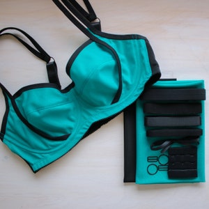 May include: Teal and black underwire bra with adjustable straps and a hook and eye closure. The bra is packaged with a set of black elastic straps and hooks.