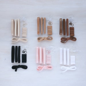 May include: Set of bra strap extenders in six different colors: black, white, beige, brown, pink, and light pink. Each set includes two straps, a hook and eye closure, and a small piece of elastic.