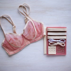 May include: A pink and cream lingerie bra with a sheer mesh fabric and a set of bra straps, elastic, and hardware for sewing.