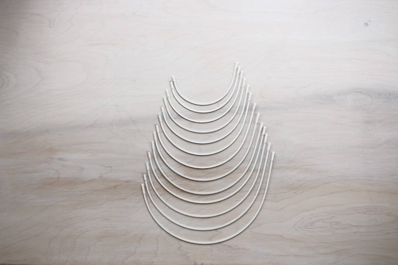 May include: A set of 10 silver-colored metal hoops of varying sizes, arranged in a pyramid shape on a light wood surface.