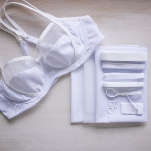 May include: White bra with mesh detailing and a set of white fabric, elastic, and hardware for bra making.