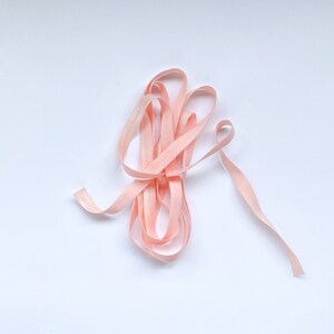 May include: A close-up of a pink elastic ribbon, coiled and ready for use in crafting or sewing projects.