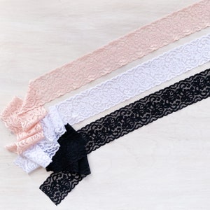 May include: Three different lace trims in pink, white, and black. The lace trims are delicate and have a floral pattern.