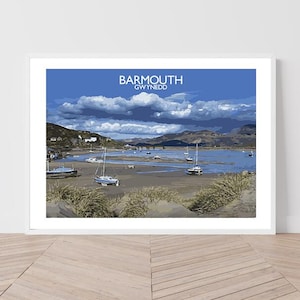 May include: A framed print of Barmouth, Gwynedd, featuring a coastal scene with sailboats on the water. The sky is blue with white clouds, and the land is visible in the background. The print is in a white frame.