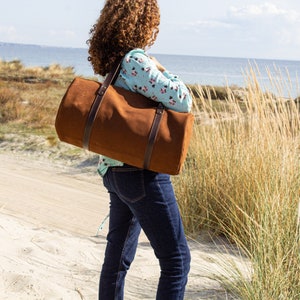 A woman model carries a round, tobacco-colored, authentic Italian leather handcrafted travel purse.