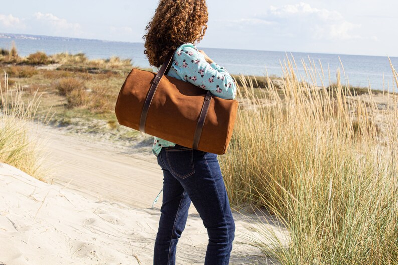 A woman model carries a round, tobacco-colored, authentic Italian leather handcrafted travel purse.