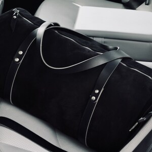 Handcrafted round duffel bag in black color, with detachable and adjustable long strap, from soft true Italian leather, ideal trip companion.