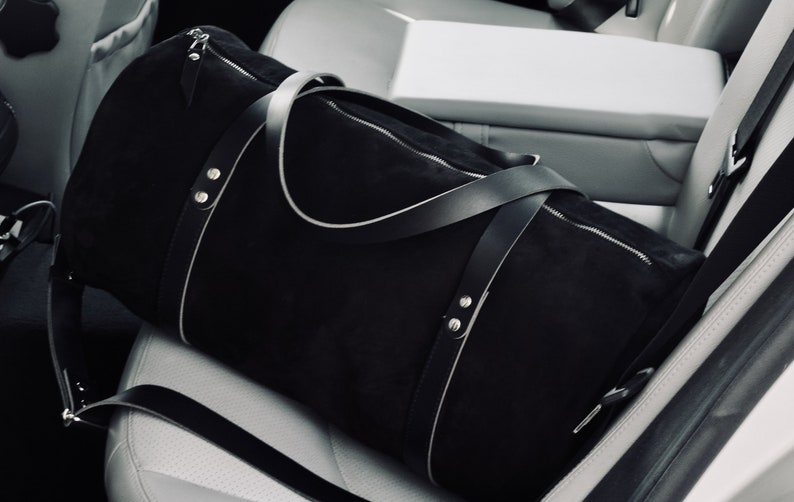 Handcrafted round duffel bag in black color, with detachable and adjustable long strap, from soft true Italian leather, ideal trip companion.