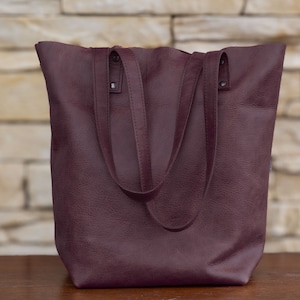 Handmade Italian leather tote with open and zipped exterior pockets, top zipper and long strap in cinnamon color.