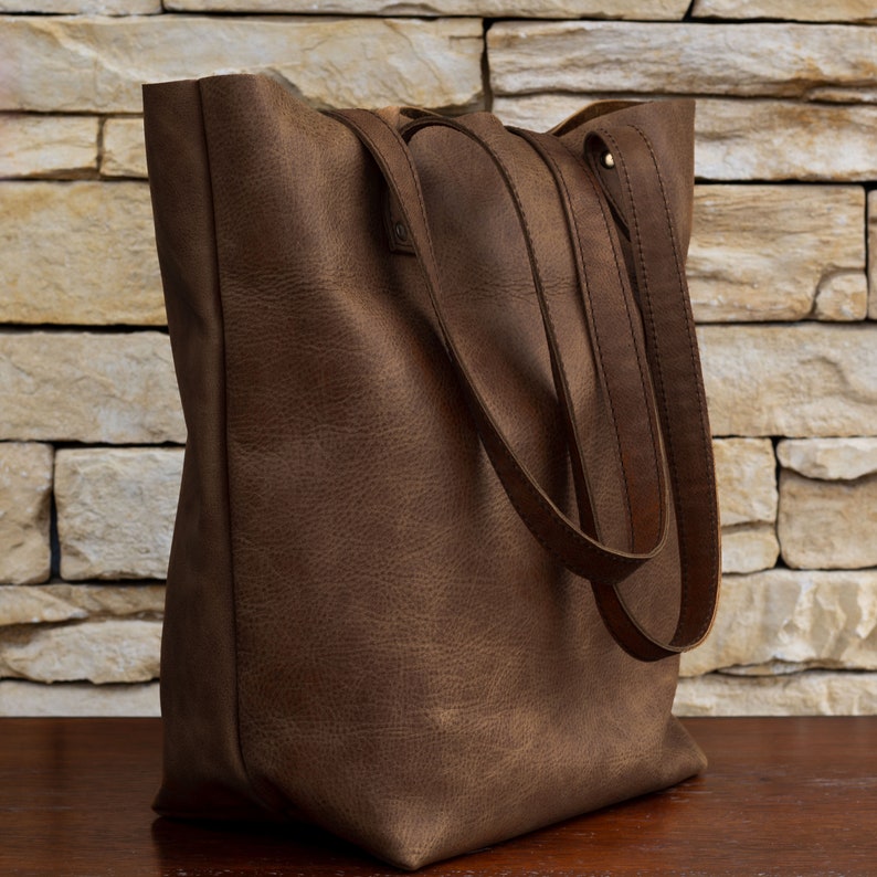 Handmade Italian leather tote with open and zipped exterior pockets, top zipper and long strap in cognac color.