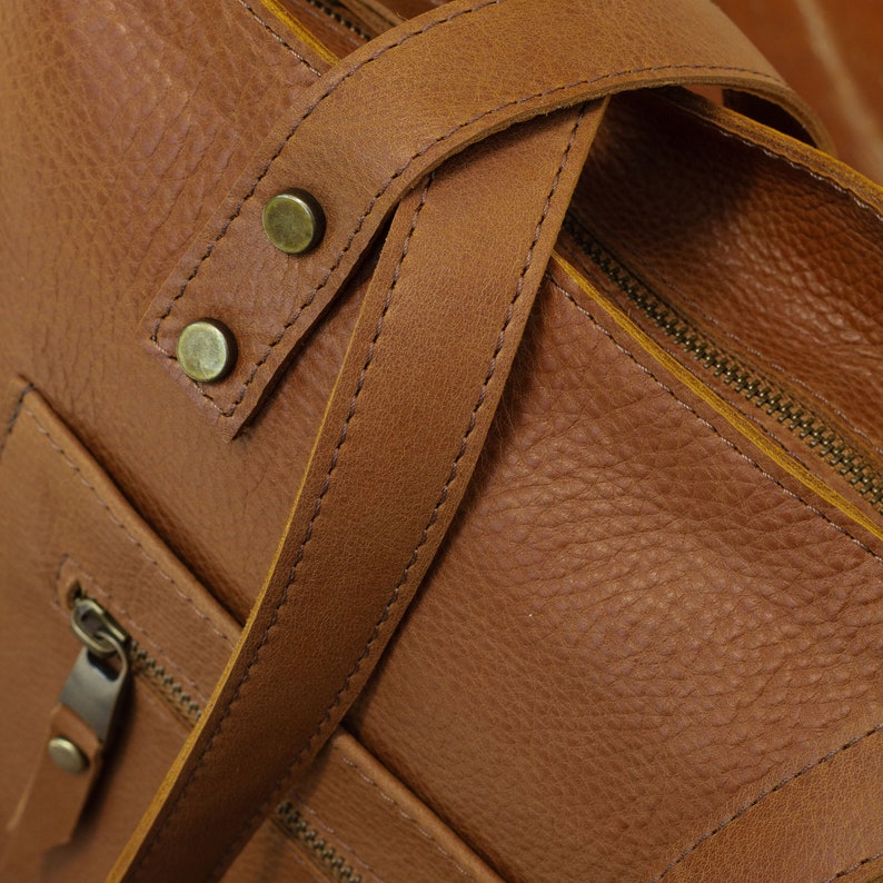 The handmade Italian leather tote with top zipper and long strap in mattone color features a front double pocket.