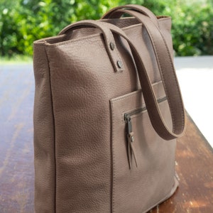 Handmade Italian leather tote with open and zipped exterior pockets, top zipper and long strap in noce color.