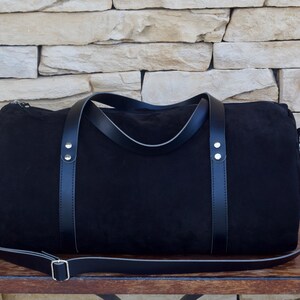 Handcrafted round duffel bag in black color, with detachable and adjustable long strap, from soft true Italian leather.