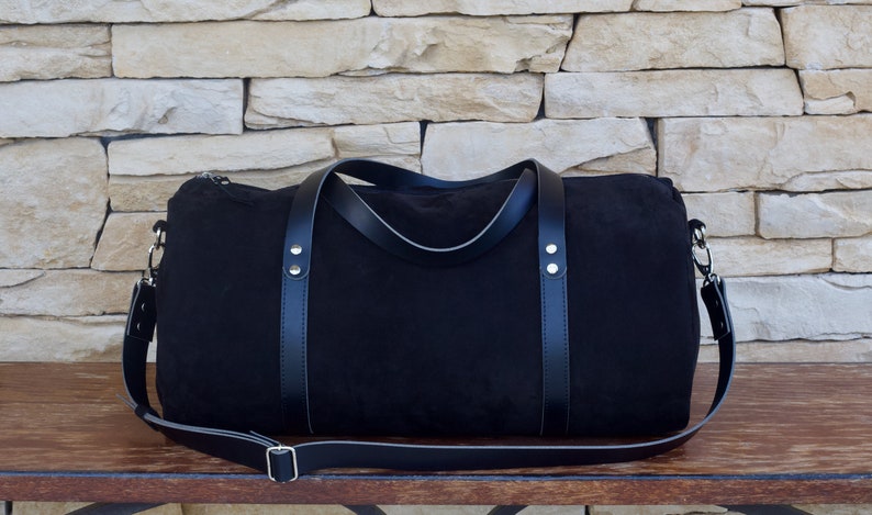 Handcrafted round duffel bag in black color, with detachable and adjustable long strap, from soft true Italian leather.