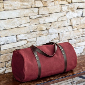 Handcrafted round shaped travel bag in bordo hue soft Italian leather.