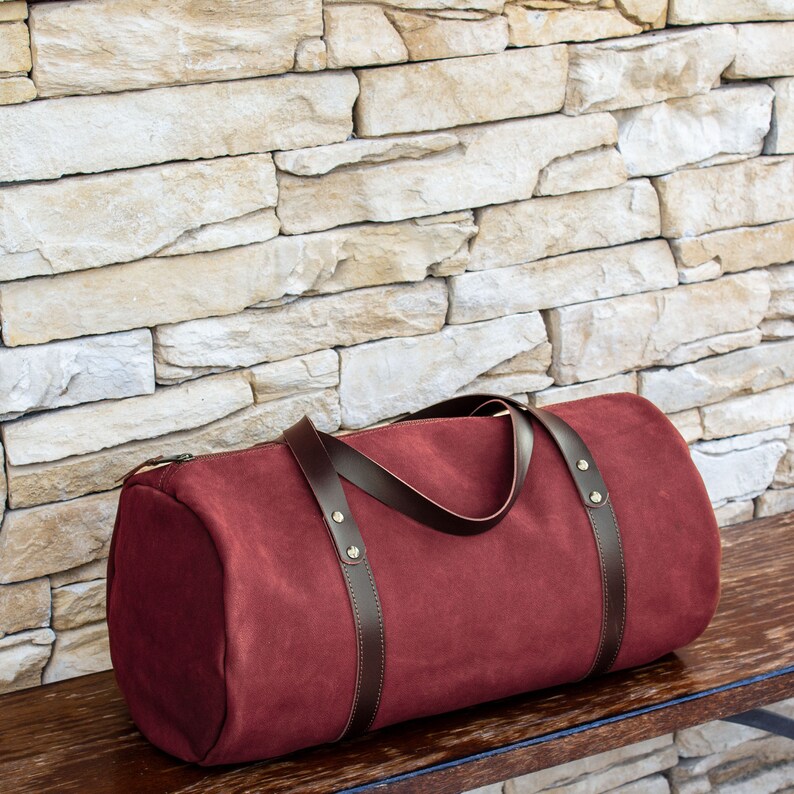 Handcrafted round shaped travel bag in bordo hue soft Italian leather.