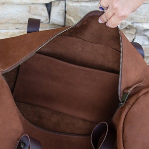 A close-up of the interior of a round, tobacco-colored travel bag made by hand from real Italian leather.