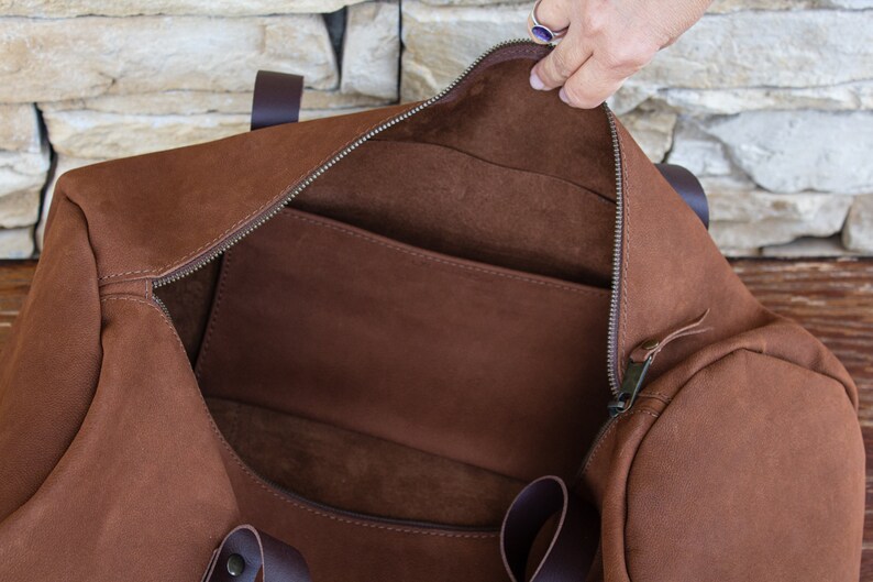 A close-up of the interior of a round, tobacco-colored travel bag made by hand from real Italian leather.