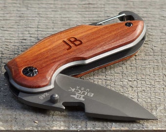 May include: Two personalized pocket knives with wooden handles. The knives have a silver blade and a small bottle opener. The handles are engraved with the initials "NA" and "JB".