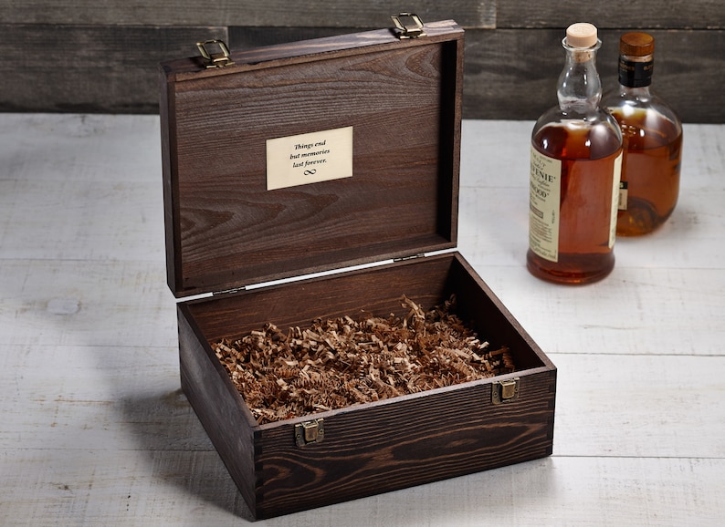 May include: A dark brown wooden box with a hinged lid and brass clasps. The box is open and filled with brown packing paper. The inscription "Things end but memories last forever" is visible on the inside of the lid.