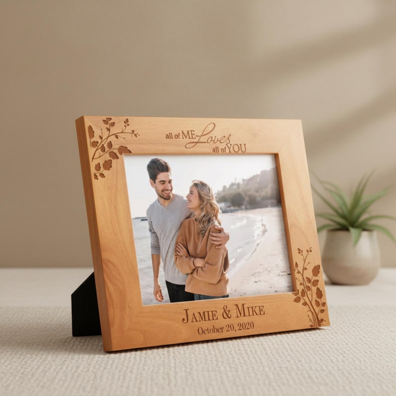 May include: A light-colored wooden picture frame with a photograph of a couple. The frame has decorative floral accents and the text "all of ME Loves all of YOU" and "JAMIE & MIKE October 20, 2020".