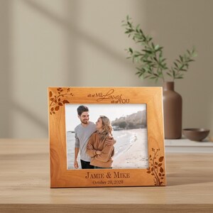 May include: A wooden picture frame with a photo of a couple on a beach. The frame has the text "all of ME Loves all of YOU" and "JAMIE & MIKE October 20, 2020". Decorative floral elements are etched into the wood.