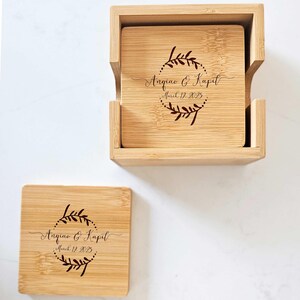 May include: Set of four bamboo coasters with a wooden box. The coasters are engraved with a wreath design and the text "Angiao & Kapil, March 17, 2023".