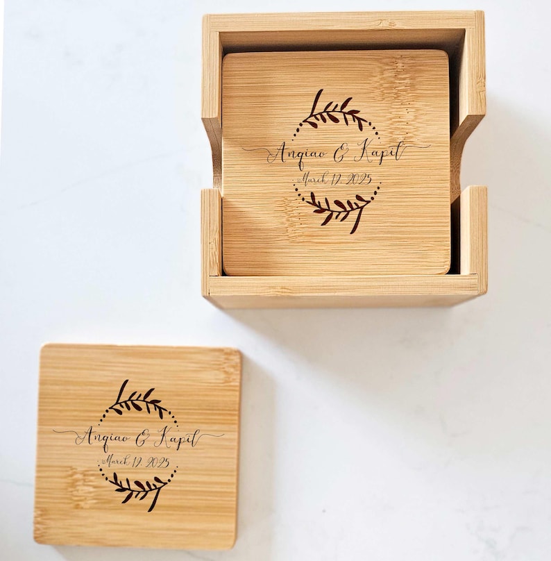 May include: Set of four bamboo coasters with a wooden box. The coasters are engraved with a wreath design and the text "Angiao & Kapil, March 17, 2023".