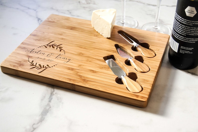 May include: A personalized bamboo cheese board with four cheese knives and a block of cheese. The board is engraved with the text "Austin & Henry June 18, 2017".