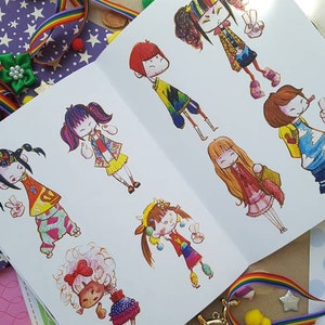 May include: A sketchbook filled with colorful illustrations of cartoon characters wearing different outfits. The characters are drawn in a whimsical style with bright colors and bold lines.