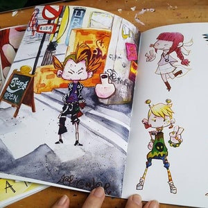 May include: An open sketchbook with colorful illustrations of cartoon characters. The characters are wearing different styles of clothing and have unique hairstyles. The sketchbook is open to a page with a character standing in front of a building with a sign that says "Today's Special".