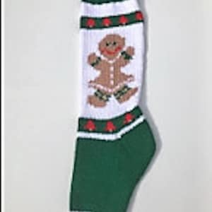May include: Green and white knitted Christmas stocking with a gingerbread person design. The stocking has a white cuff and a green toe.