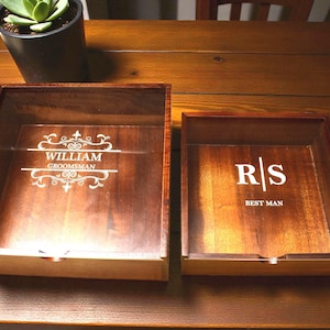 May include: Two wooden boxes with engraved text. The larger box reads "WILLIAM GROOMSMAN" and the smaller box reads "R|S BEST MAN". Both boxes are open, revealing the engraved text on the bottom.