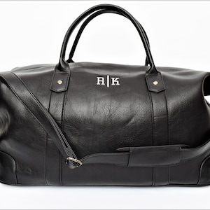 May include: Black leather duffel bag with a shoulder strap and top handles. The bag has a monogrammed "R|K" on the front.
