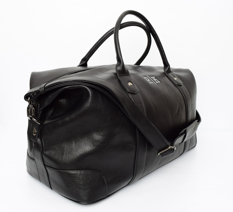 May include: A black leather duffel bag with a top handle and a shoulder strap. The bag has a zipper closure and a monogrammed "R.K." on the front.