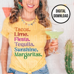 以下が含まれることがあります： 「Tacos. Lime. Fiesta. Tequila. Sunshine. Margaritas.」と虹色の文字がプリントされた黄色のTシャツ。女性がTシャツを着て、透明なグラスにマルガリータを持っている。
