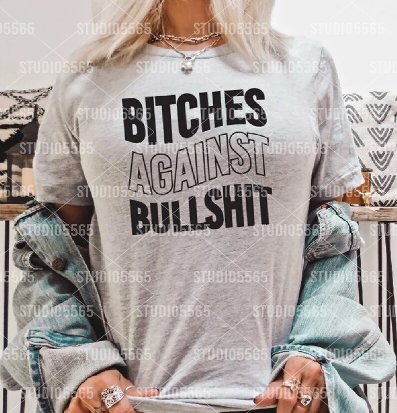Puede incluir: Una camiseta gris con el texto "BITCHES AGAINST BULLSHIT" impreso en negro.
