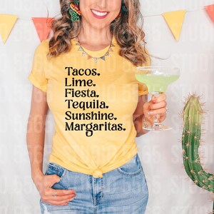 以下が含まれることがあります： 黄色のTシャツを着た女性が、「Tacos. Lime. Fiesta. Tequila. Sunshine. Margaritas.」と書かれたTシャツを着ています。彼女は透明なグラスにマルガリータを持っています。