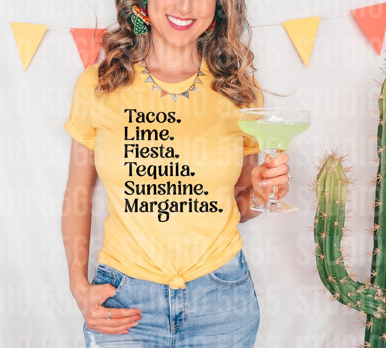 以下が含まれることがあります： 黄色のTシャツを着た女性が、「Tacos. Lime. Fiesta. Tequila. Sunshine. Margaritas.」と書かれたTシャツを着ています。彼女は透明なグラスにマルガリータを持っています。