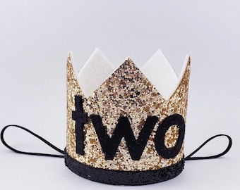 May include: Gold glitter crown with a black felt band and elastic strap. The crown has the word "two" in black felt letters.