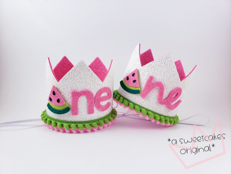 May include: A white felt crown with pink felt trim and green pom-poms. The crown has a pink felt "one" with a watermelon graphic on the side.