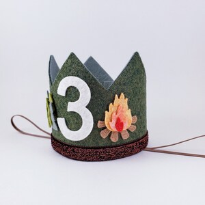 May include: Green felt crown with a white felt number "3" and a felt campfire design. The crown has a brown felt band and a brown string tie.