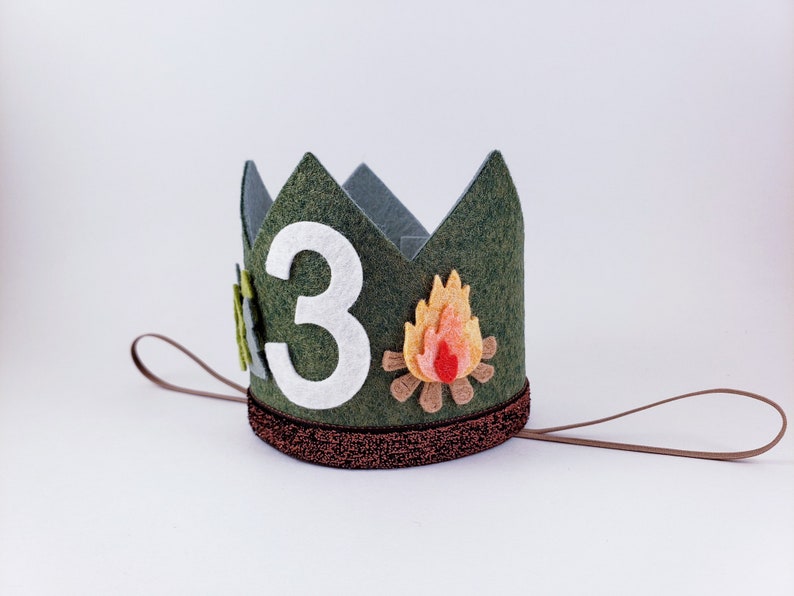 May include: Green felt crown with a white felt number "3" and a felt campfire design. The crown has a brown felt band and a brown string tie.