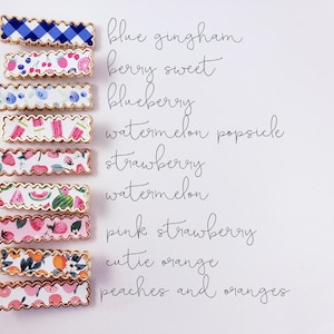May include: Ten hair clips with different fruit and floral patterns. The patterns include blue gingham, berry sweet, blueberry, watermelon popsicle, strawberry, watermelon, pink strawberry, cutie orange, and peaches and oranges.